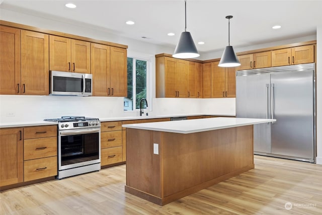 kitchen with appliances with stainless steel finishes, a center island, pendant lighting, and light countertops