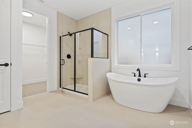 bathroom featuring a soaking tub, a walk in closet, and a stall shower