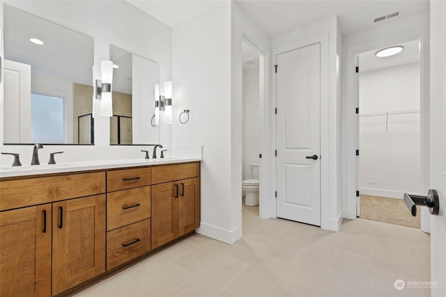 full bathroom with toilet, a shower stall, a spacious closet, and a sink