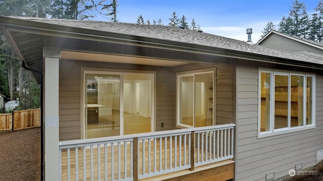 view of side of home featuring a shingled roof, crawl space, and fence