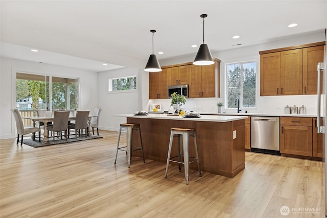 kitchen with decorative light fixtures, stainless steel appliances, light countertops, and a center island