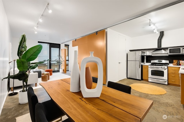 dining area featuring rail lighting and a barn door