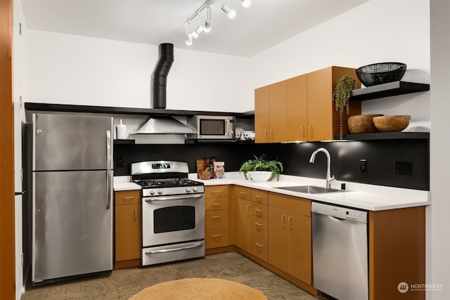 kitchen with rail lighting, appliances with stainless steel finishes, sink, and wall chimney range hood