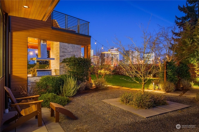 yard at dusk featuring a balcony