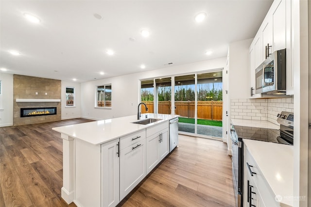 kitchen featuring stainless steel appliances, sink, a center island with sink, and white cabinets