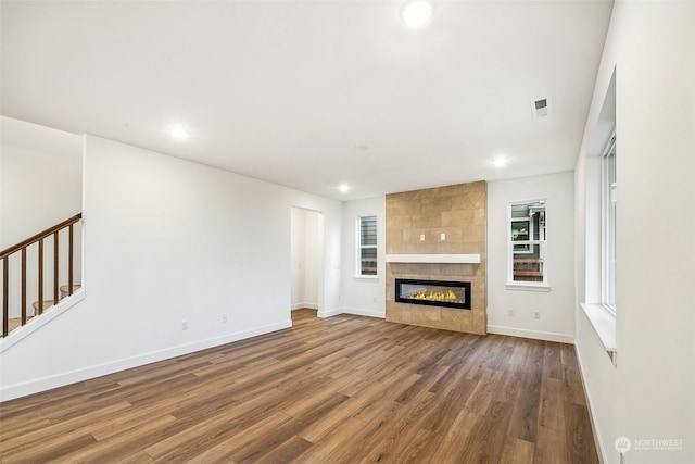 unfurnished living room featuring a tile fireplace and hardwood / wood-style floors