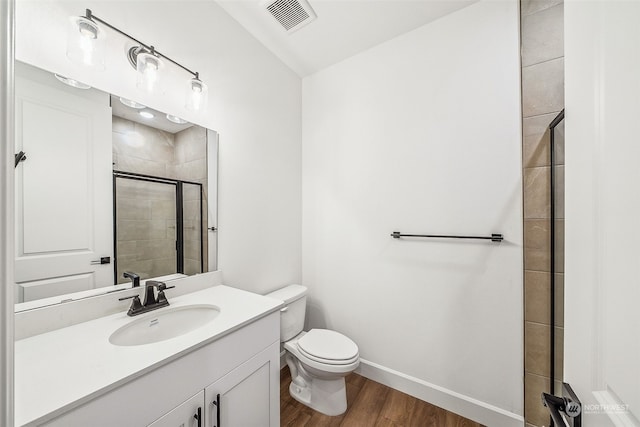 bathroom featuring vanity, hardwood / wood-style flooring, a shower with shower door, and toilet