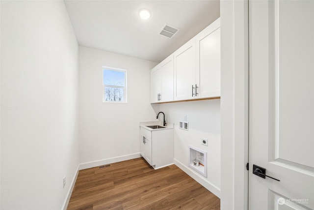 washroom featuring sink, hardwood / wood-style flooring, cabinets, hookup for a washing machine, and electric dryer hookup