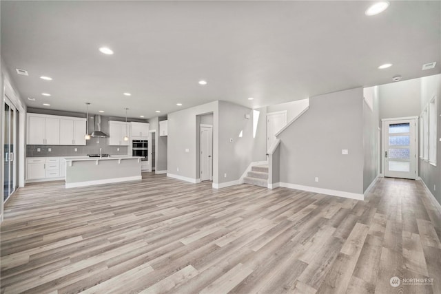 unfurnished living room with sink and light hardwood / wood-style floors