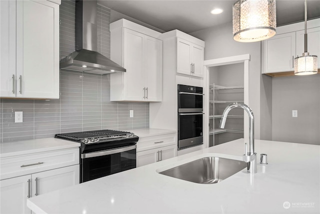 kitchen with wall chimney exhaust hood, sink, white cabinetry, range with gas stovetop, and black double oven