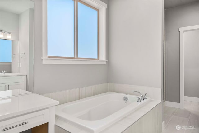 bathroom featuring a relaxing tiled tub, vanity, and tile patterned flooring