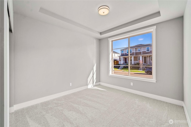 carpeted empty room featuring a tray ceiling