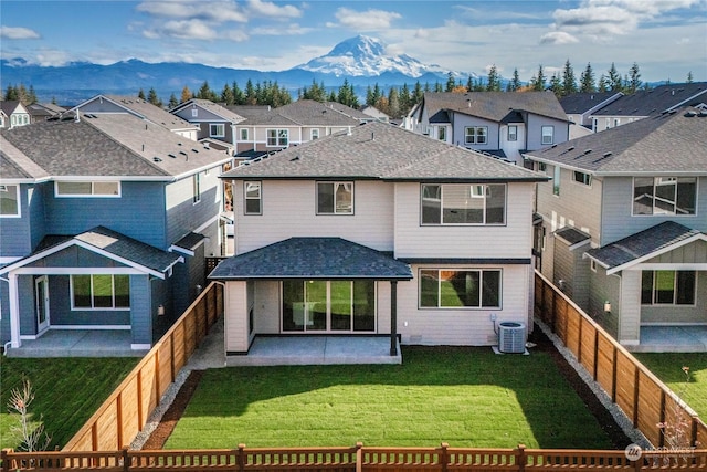 rear view of house featuring central AC unit, a patio area, a lawn, and a mountain view