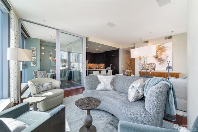 living room with hardwood / wood-style floors, a chandelier, and a wall of windows