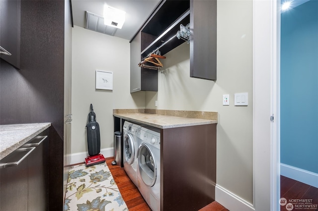 laundry room with dark wood-type flooring, cabinets, and washer and clothes dryer