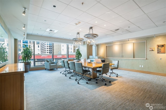 carpeted dining area featuring a paneled ceiling