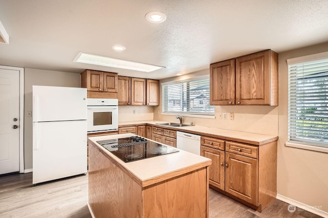 kitchen featuring a center island, sink, white appliances, and light hardwood / wood-style flooring