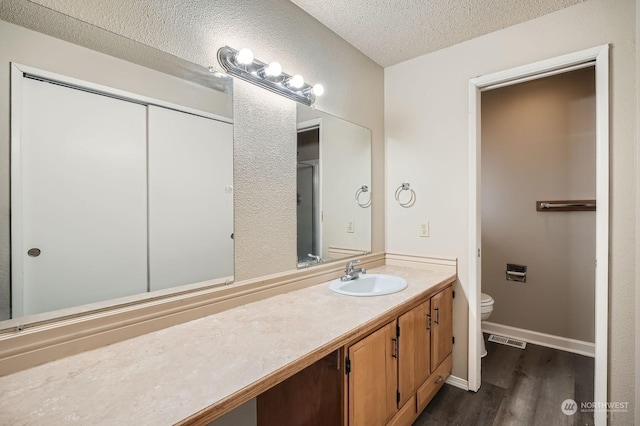 bathroom with wood-type flooring, vanity, a textured ceiling, and toilet