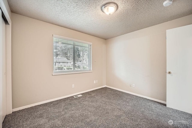 carpeted empty room featuring a textured ceiling