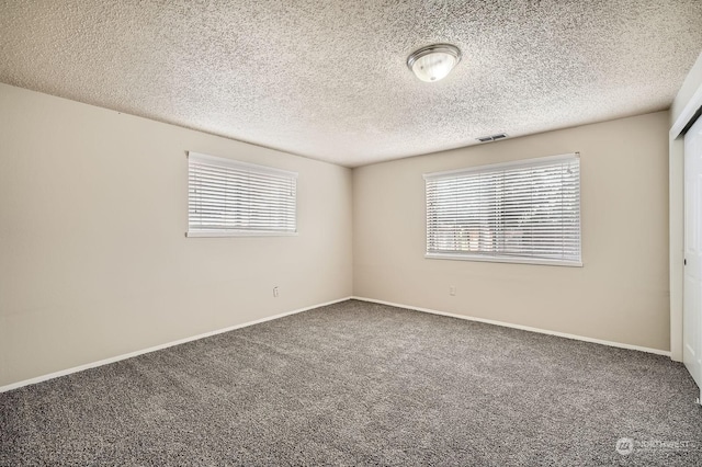 carpeted empty room featuring a textured ceiling