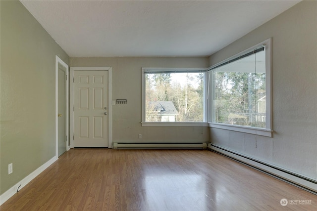 spare room with light wood-type flooring and a baseboard heating unit