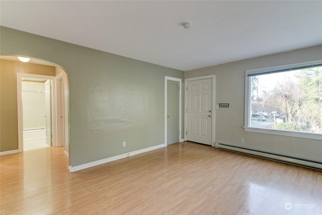 spare room with a baseboard radiator and light wood-type flooring