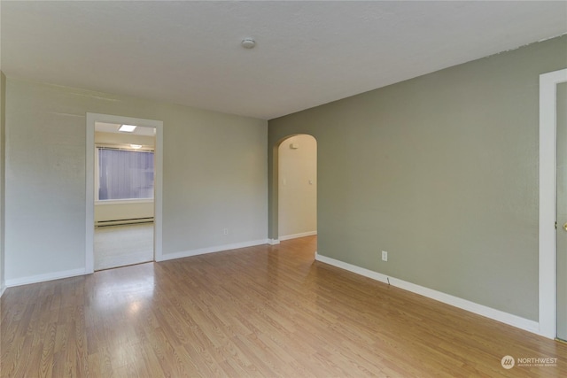 empty room featuring light hardwood / wood-style floors and a baseboard heating unit