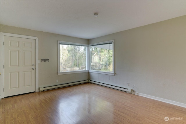 empty room featuring baseboard heating and light hardwood / wood-style flooring