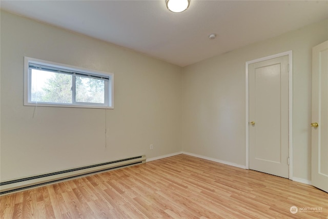 spare room with a baseboard radiator and light hardwood / wood-style flooring