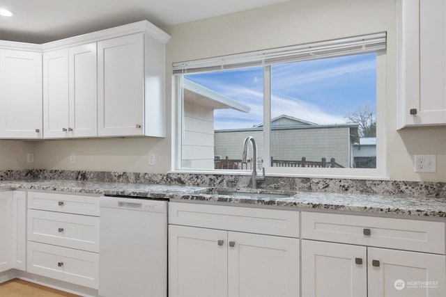 kitchen featuring white cabinetry, white dishwasher, sink, and light stone counters