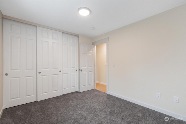 unfurnished bedroom featuring a closet and dark colored carpet