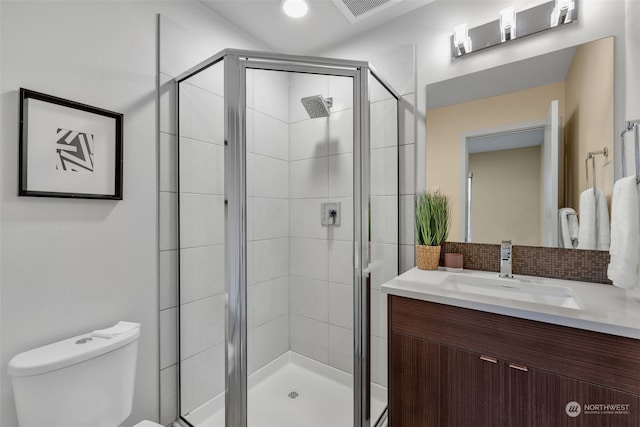 bathroom featuring tasteful backsplash, vanity, a shower with shower door, and toilet