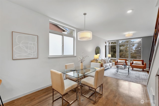 dining space with a wealth of natural light, hardwood / wood-style floors, and a wall of windows