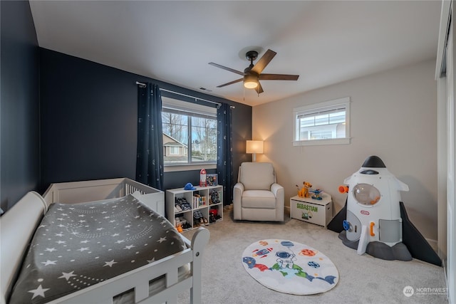 bedroom with light carpet, a crib, and ceiling fan