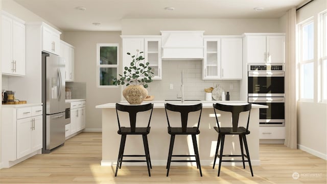 kitchen featuring sink, appliances with stainless steel finishes, a kitchen island with sink, a kitchen breakfast bar, and white cabinets