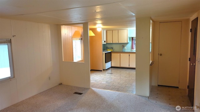 kitchen featuring light carpet, white electric range, visible vents, light countertops, and light floors