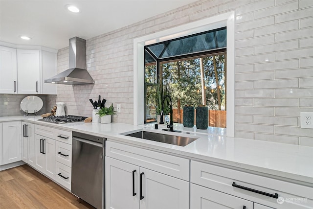 kitchen with white cabinetry, wall chimney range hood, sink, and appliances with stainless steel finishes