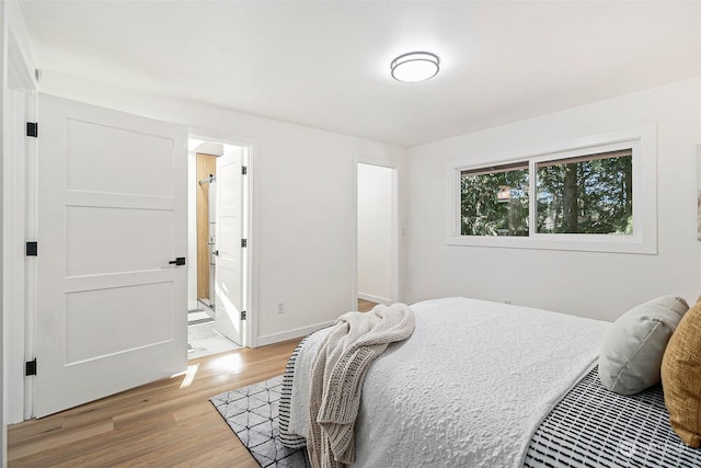 bedroom featuring ensuite bath and light hardwood / wood-style floors