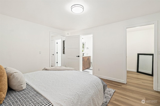 bedroom with ensuite bathroom and light hardwood / wood-style flooring