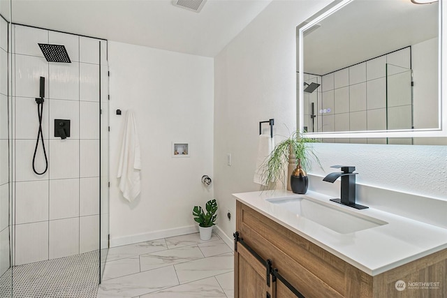 bathroom with tiled shower and vanity