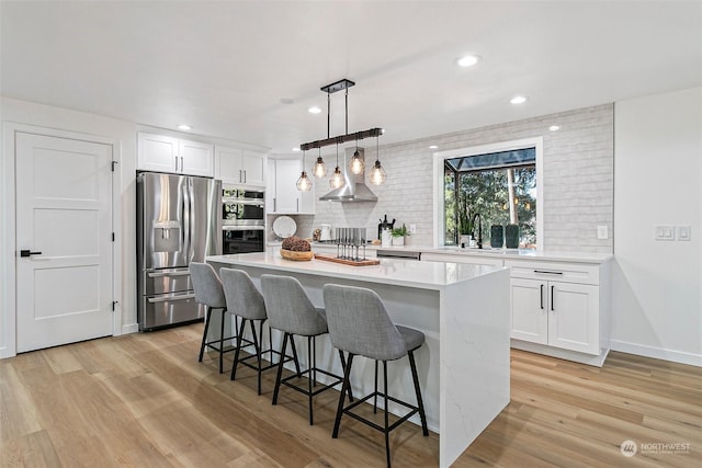 kitchen featuring sink, white cabinetry, decorative light fixtures, appliances with stainless steel finishes, and a kitchen island