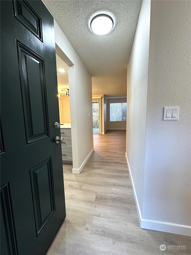 corridor featuring a textured ceiling and light wood-type flooring