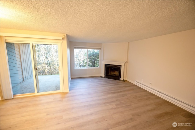 unfurnished living room featuring a baseboard radiator, light hardwood / wood-style flooring, and a textured ceiling