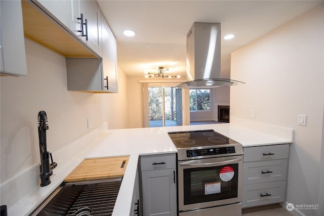 kitchen with stainless steel electric range, gray cabinets, kitchen peninsula, and island exhaust hood