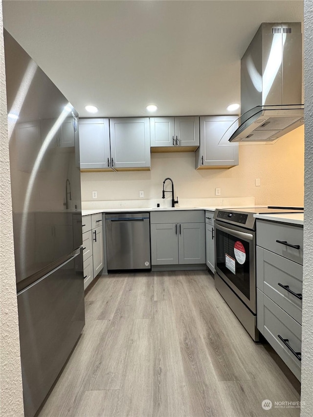 kitchen with sink, gray cabinetry, stainless steel appliances, island exhaust hood, and light wood-type flooring