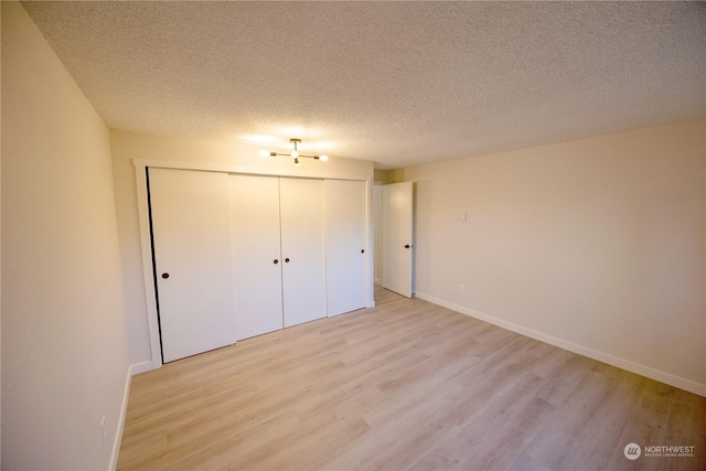 unfurnished bedroom featuring a closet, a textured ceiling, and light hardwood / wood-style flooring