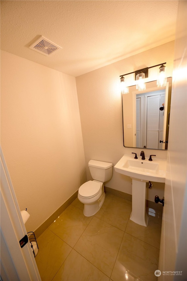 bathroom with toilet, tile patterned flooring, and a textured ceiling