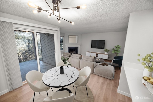 dining area featuring a notable chandelier, light hardwood / wood-style floors, and a textured ceiling