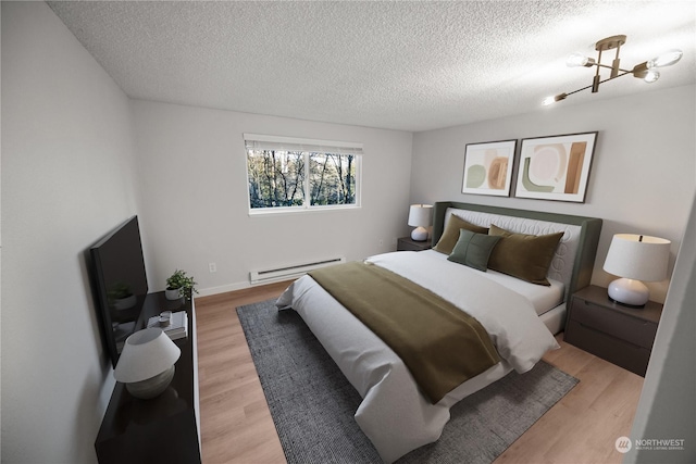 bedroom featuring light hardwood / wood-style floors, a textured ceiling, and baseboard heating