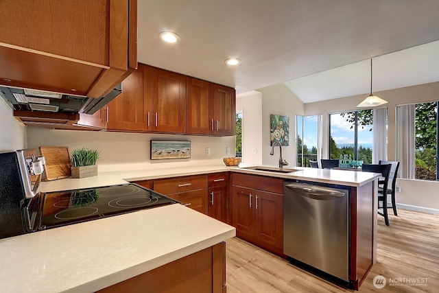 kitchen featuring light countertops, appliances with stainless steel finishes, brown cabinetry, a sink, and a peninsula